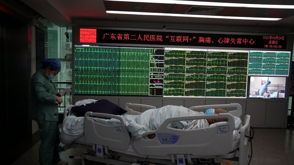 A patient moves past a display showing the real-time electrocardiograms of patients at the department of cardiovascular medicine of the Guangdong Second Provincial General Hospital in Guangzhou, in southern China's Guangdong province, Sunday, Sept. 2