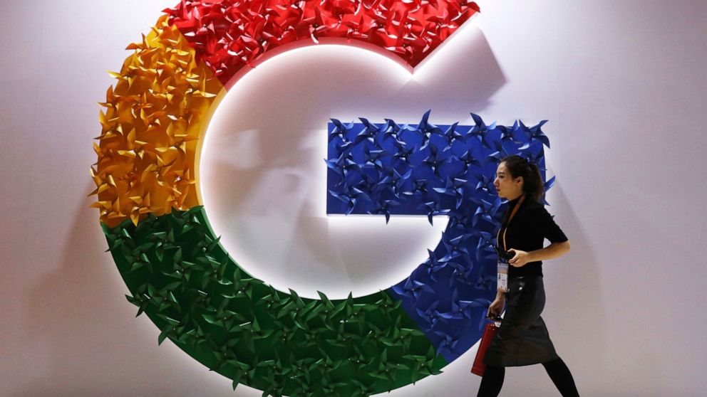 FILE - In this Monday, Nov. 5, 2018 file photo, a woman walks past the logo for Google at the China International Import Expo in Shanghai. Google says it's making progress on plans to revamp Chrome user tracking technology aimed at improving privacy 