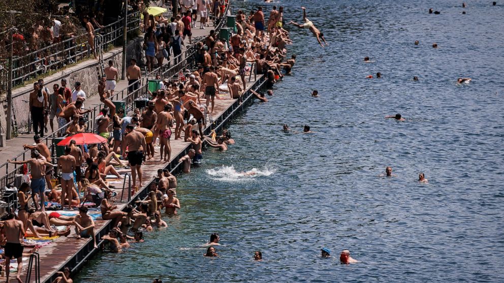 People swim in the river Limmat at Letten, in Zurich, Switzerland, Saturday, June 18, 2022. People flocked to parks and pools across Western Europe on Saturday for a bit of respite from an early heat wave that saw the mercury rise above 40 Cs (104 F)