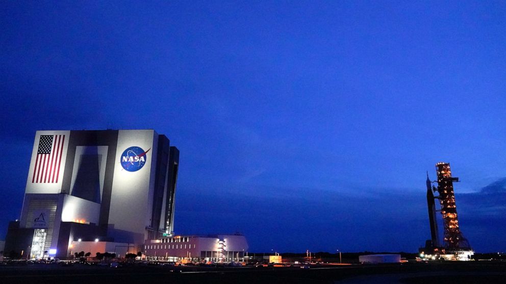 The NASA moon rocket, right, slated for the Artemis mission to the moon rolls back to the Vehicle Assembly Building at the Kennedy Space Center Tuesday, Sept. 27, 2022, in Cape Canaveral, Fla. The launch of the rocket was postponed due to the impendi