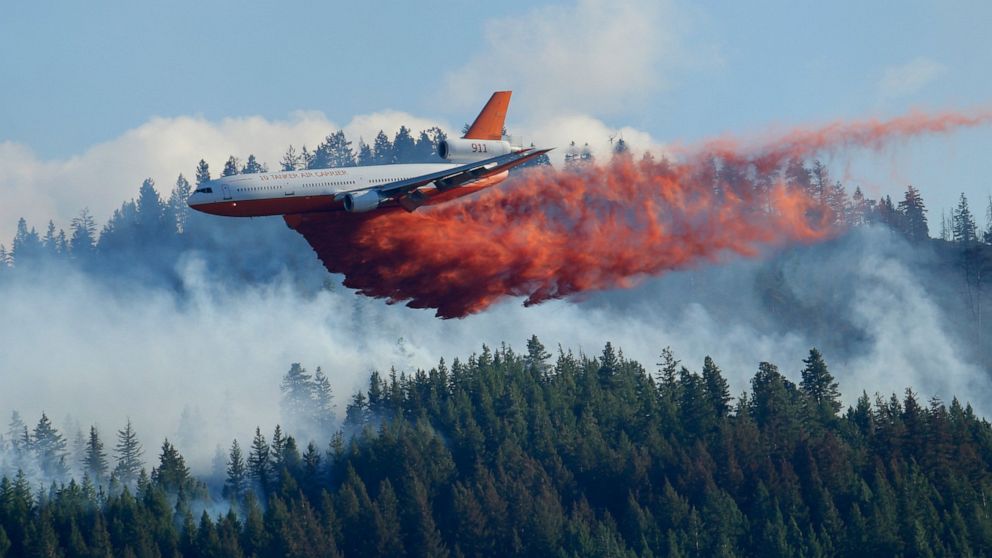 FILE - In this Aug. 21, 2015 file photo, a tanker airplane drops fire retardant on a wildfire burning near Twisp, Wash. Newly released national plans for fighting wildfires during the coronavirus pandemic are hundreds of pages long but don't offer ma