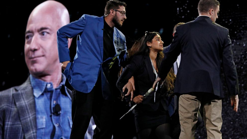 Security removes a protestor, second from left, from the stage as Amazon CEO Jeff Bezos speaks at the the Amazon re:MARS convention, Thursday, June 6, 2019, in Las Vegas. (AP Photo/John Locher)