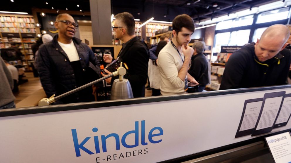 Customers stand near a display of Kindle electronic readers at the opening day for Amazon Books, the first brick-and-mortar retail store for online retail giant Amazon, Nov. 3, 2015, in Seattle. Amazon said Thursday, June 2, 2022 it will shut down it