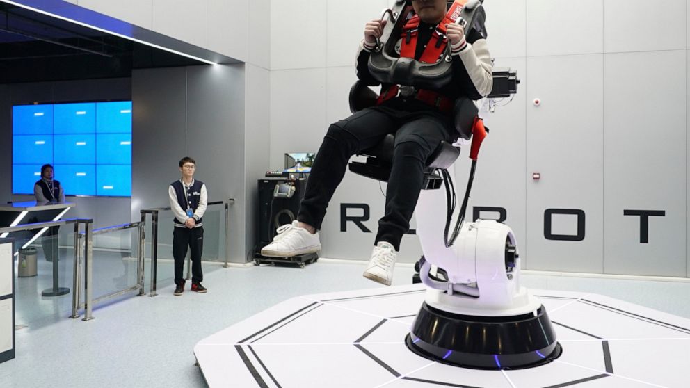 In this April 2, 2019, photo, a visitor rides a virtual roller coaster ride operated by a robotic arm in a VR theme park in Nanchang, China. One of the largest virtual reality theme parks in the world has opened its doors in southwestern China, sport