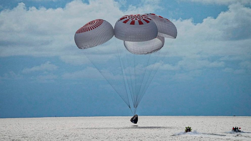 In this image taken provided by SpaceX, a capsule carrying four people parachutes into the Atlantic Ocean off the Florida coast, Saturday, Sept. 18, 2021. The all-amateur crew was the first to circle the world without a professional astronaut. (Space