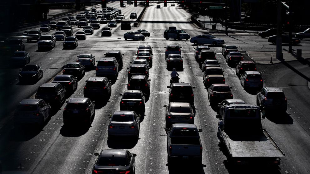 FILE - In this April 22, 2021 file photo, cars wait at a red light during rush hour at the Las Vegas Strip, in Las Vegas. Two organizations that influence many Americans’ automobile buying decisions will begin rating vehicles on how well they track b