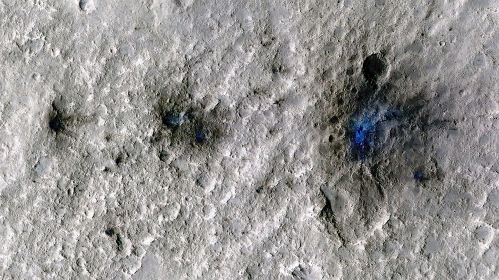 This undated photo released by NASA shows craters that were formed by a Sept. 5, 2021, meteoroid impact on Mars, the first to be detected by NASA’s InSight. Taken by NASA’s Mars Reconnaissance Orbiter, this enhanced-color image highlights the dust an