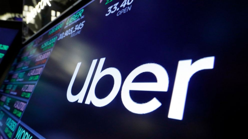 FILE - In this Friday, Aug. 16, 2019 file photo, the logo for Uber appears above a trading post on the floor of the New York Stock Exchange. London transport authorities are giving ride-hailing firm Uber two months to continue operating in the city r