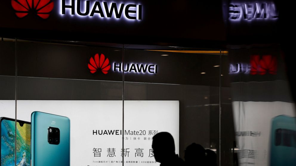 FILE - In this May 29, 2019 file photo, a man walks past a Huawei retail store in Beijing. On Friday, June 21, 2019, the United States blacklisted five Chinese organizations, calling them national security threats and cutting them off from critical U