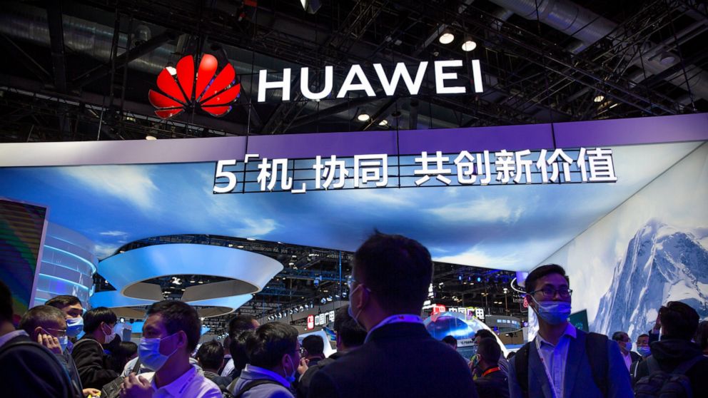 FILE - In this Wednesday, Oct. 14, 2020 file photo, attendees wearing face masks to protect against the coronavirus walk past a booth from Chinese technology firm Huawei at the PT Expo in Beijing. The Swedish telecom regulator said Tuesday Oct. 20, 2