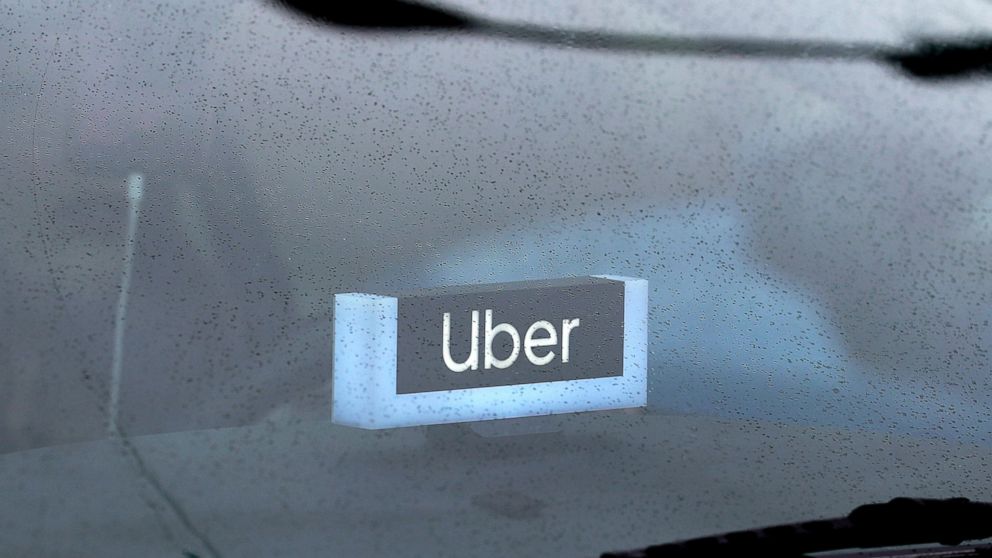 FILE - In this May 15, 2020 file photo, an Uber sign is displayed inside a car in Chicago. Uber’s food delivery business brought in more money during the third quarter than its signature rides business. It was a sign of how much consumer behavior has
