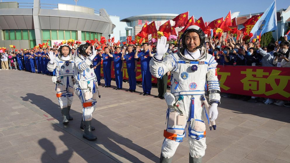 In this photo released by Xinhua News Agency, Chinese astronaut Chen Dong, right, waves as he walks ahead of fellow astronauts Liu Yang and Cai Xuzhe during a sendoff ceremony for the Shenzhou-14 crewed space mission at the Jiuquan Satellite Launch C