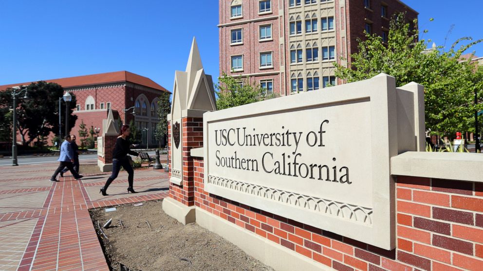 FILE - In this March 12, 2019 file photo people walk at the University Village area of the University of Southern California in Los Angeles. USC is among three universities and a health care institution who are sharing a gift of more than $1 billion 