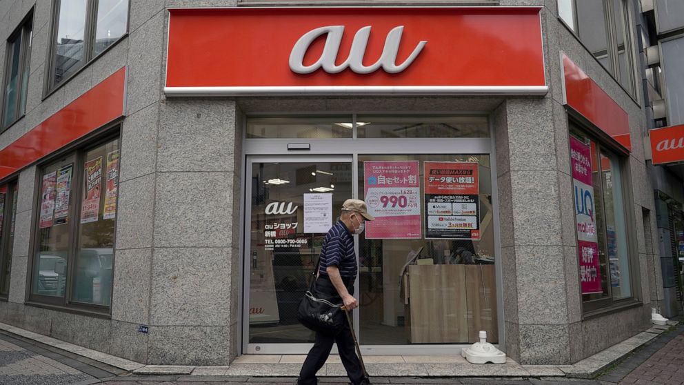 A person walks past an "au" mobile brand operator shop, of KDDI Corp., Monday, July 4, 2022, in Tokyo. Many users of Japan’s No. 2 mobile carrier KDDI Corp. were still having trouble making calls Monday after a massive outage throughout the weekend t