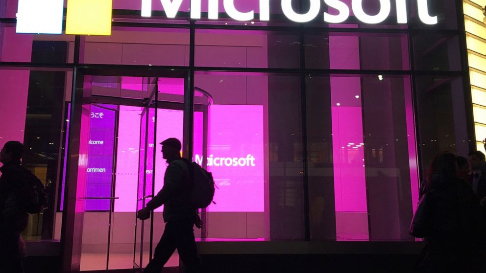 FILE - In this Nov. 10, 2016, file photo, people walk past a Microsoft office in New York. China-based government hackers have exploited a bug in Microsoft's email server software to target U.S. organizations, the company said Tuesday, March 2, 2021.