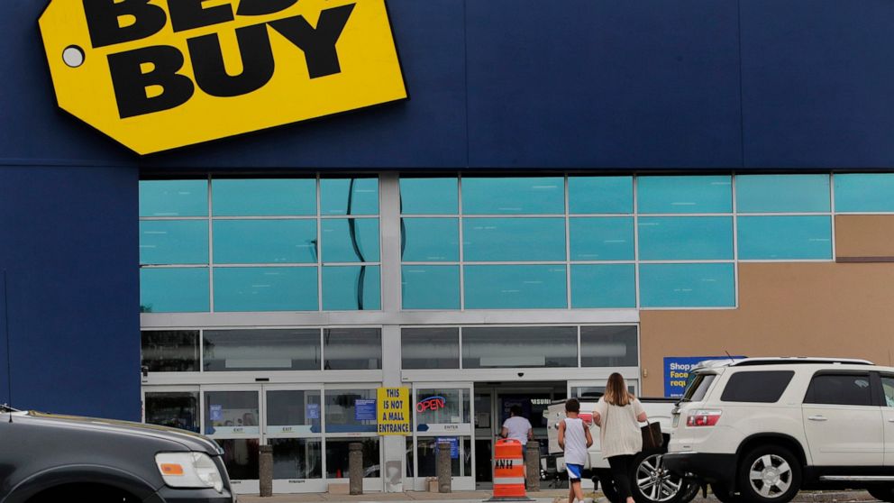 FILE - A woman walks with a boy to the Best Buy store at the Mall of New Hampshire, Tuesday, Aug. 4, 2020, in Manchester, N.H. Best Buy, the nation's largest consumer electronics chain, cut its annual sales and profit forecast Wednesday, July 27, 202