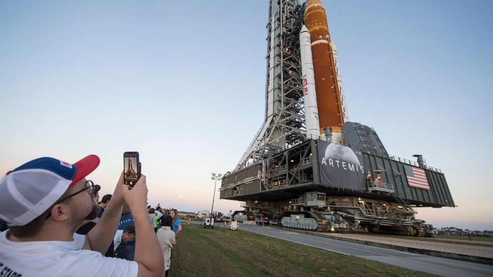 FILE - Invited guests and NASA employees take photos as NASA's Space Launch System (SLS) rocket with the Orion spacecraft aboard is rolled out of High Bay 3 of the Vehicle Assembly Building for the first time, at the Kennedy Space Center in Cape Cana