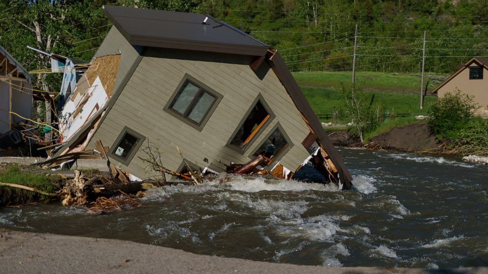 FILE - A house sits in Rock Creek after floodwaters washed away a road and a bridge in Red Lodge, Mont., on June 15, 2022. As cleanup from historic floods at Yellowstone National Park grinds on, climate experts and meteorologists say the gap between 