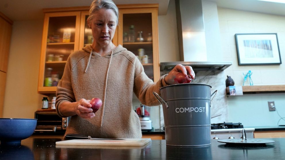 Joy Klineberg tosses an onion peel into container to be used for composting while preparing a family meal at her home in Davis, Calif., Tuesday, Nov. 30, 2021. In January 2022, new rules take effect in California requiring people to recycle their foo