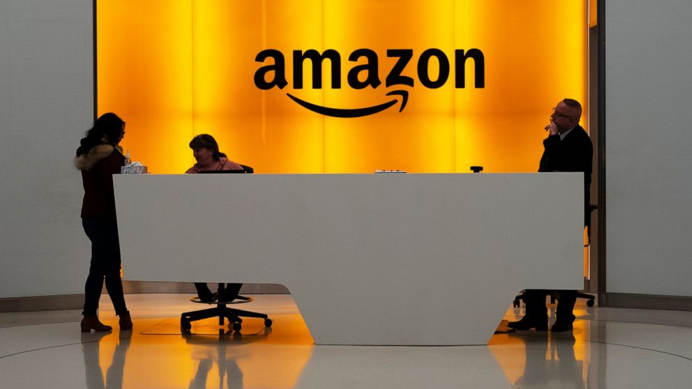 FILE - In this Feb. 14, 2019, file photo, people stand in the lobby for Amazon offices in New York. Seattle-based Amazon.com, Inc. has asked federal regulators to block multiple shareholder proposals addressing criticism company stances on curbing ha