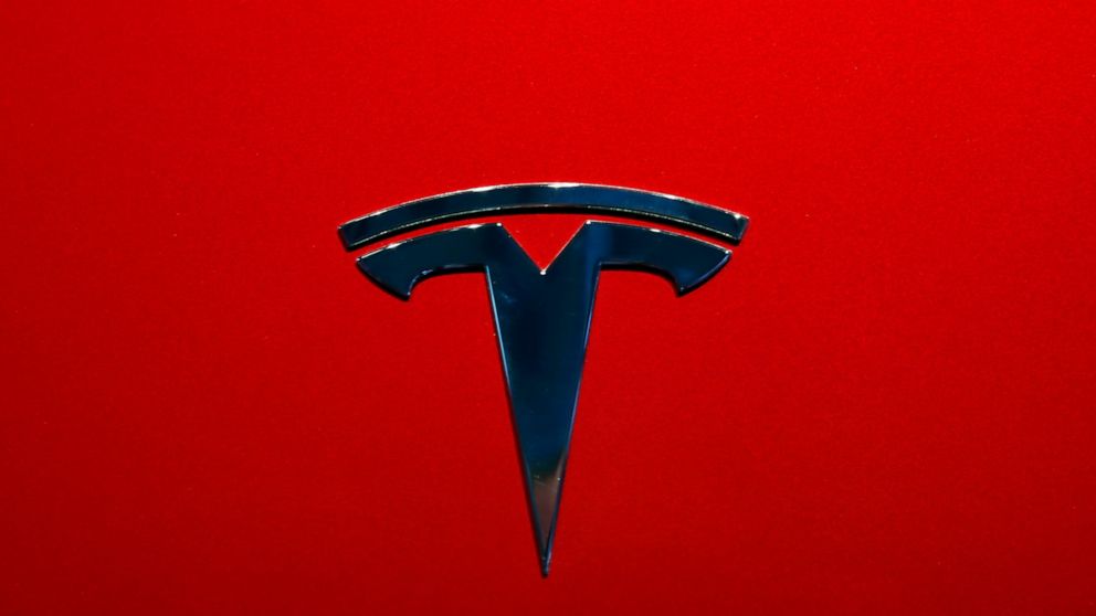 FILE- This Oct. 3, 2018, file photo shows the logo of Tesla model 3 at the Auto show in Paris. Tesla is increasing the size of its stock and debt offering to as much as $2.7 billion just one day after announcing plans to raise $2 billion in new capit
