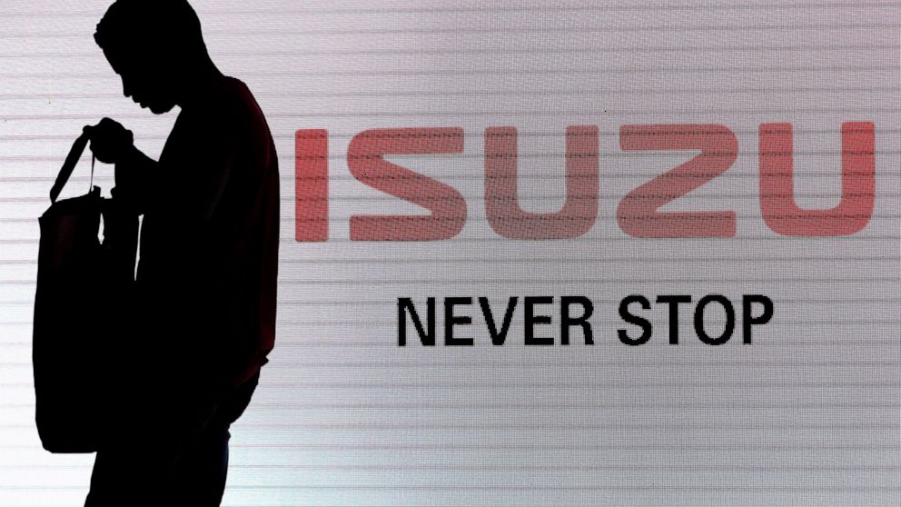 FILE - In this May 11, 2017, file photo, a man walks past the Isuzu logo during the launch of Isuzu MU-X SUV in New Delhi, India. Japanese automakers Toyota, Isuzu and Hino said Wednesday, March 24, 2021 they are setting up a partnership in commercia