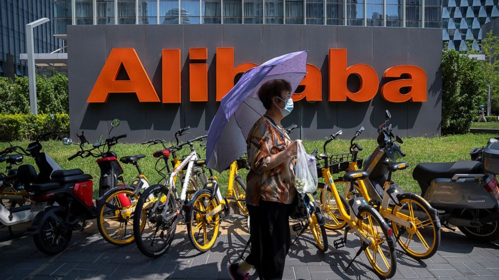 A woman holds an umbrella as she walks past the offices of Chinese e-commerce firm Alibaba in Beijing on Aug. 10, 2021. China is tightening control over data gathered by companies about the public under a law approved Friday, Aug. 20, 2021 by its cer