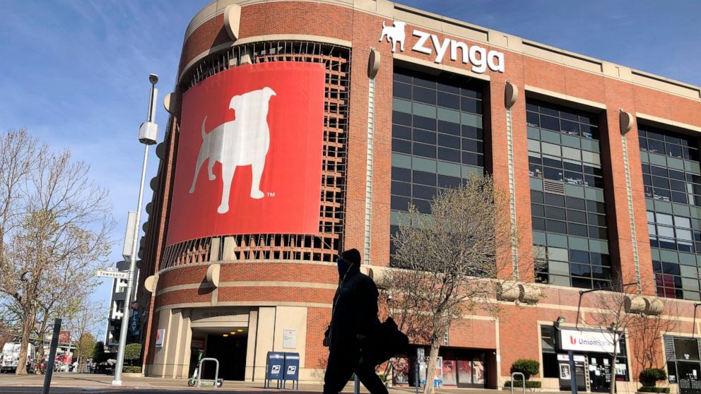 FILE - A pedestrian walks in front of a sign at Zynga in San Francisco, Tuesday, March 16, 2021. Take-Two Interactive, maker of Grand Theft Auto and Red Dead Redemption, is buying Zynga, maker of FarmVille and Words With Friends, in a cash-and-stock 