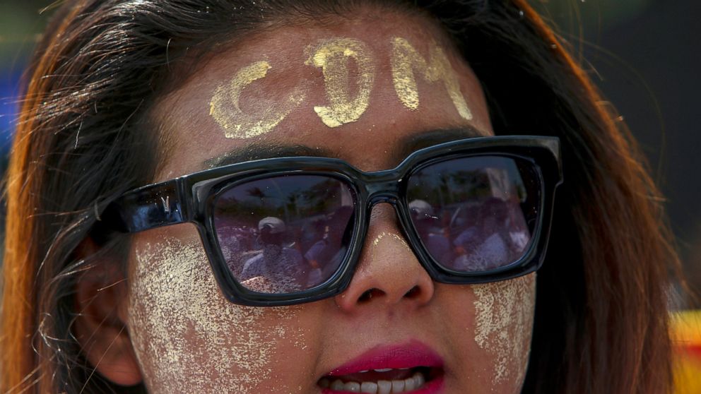 An anti-coup protester with thanaka, a traditional face paste with letters CDM, representing "Civil Disobedience Movement" shouts slogans during a street march in Mandalay, Myanmar, Thursday, Feb. 25, 2021. Protesters against the military's seizure o