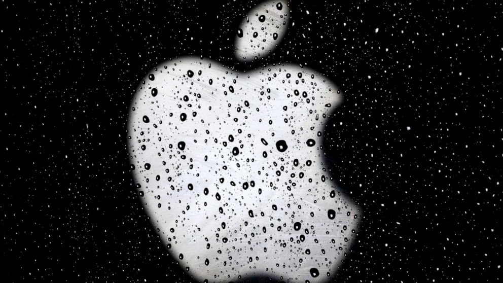 FILE - An Apple logo is seen in raindrops on a window outside an Apple Store at the Country Club Plaza shopping district in Kansas City, Mo., on Dec. 26, 2018. A former Apple employee has been charged with defrauding the tech giant out of more than $