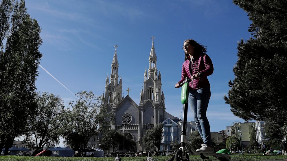 FILE - In this April 17, 2018 file photo, a woman rides a motorized scooter in Washington Square Park in San Francisco. Tired of San Francisco sidewalks being used as a testing ground for delivery robots, drones, and electric scooters, city superviso