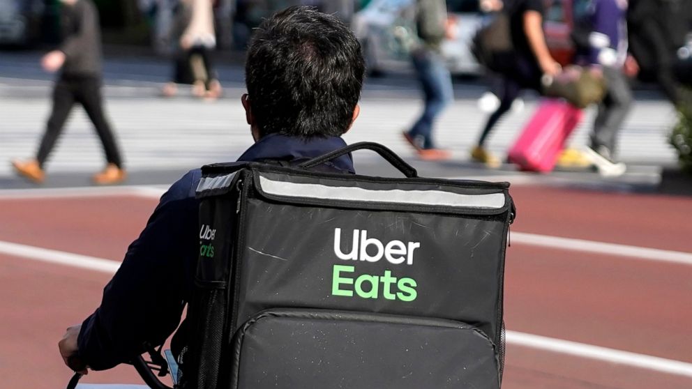 FILE - In this April 28, 2021, file photo, an Uber Eats delivery person rides a bicycle through the Shinjuku district in Tokyo, Japan. Uber’s ride-hailing service is regaining most of the momentum that it lost during the pandemic. At the same time, i