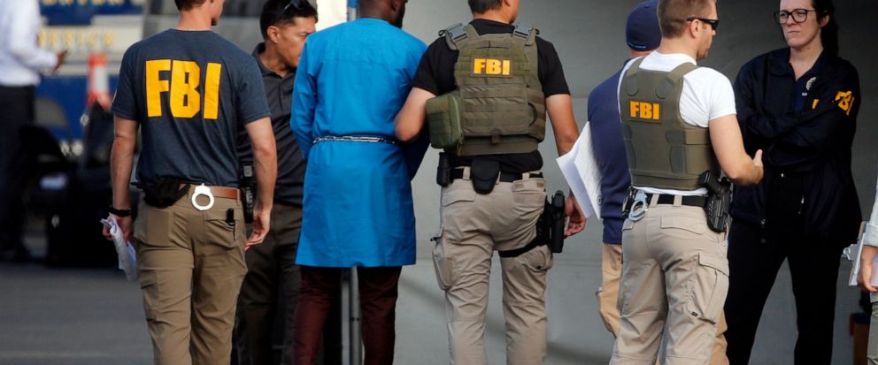 Federal agents hold a detainee, second from left, at a downtown Los Angeles parking lot after predawn raids that saw dozens of people arrested in the L.A. area Thursday, Aug. 22, 2019. U.S. authorities have unsealed a 252-count federal grand jury ind