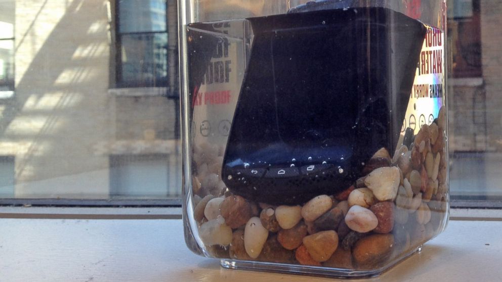 A Kyocera Brigadier cell phone sits in a container of water at the ABC News headquarters in New York City on August 14, 2014.