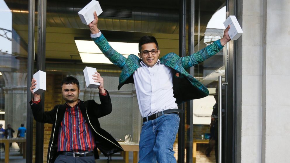 The first people in the queue, Sam Sheikh, left, and Jameel Ahmed, right, celebrate for the media after buying the new iPhone6, outside the Apple shop in London, Sept. 19, 2014. 