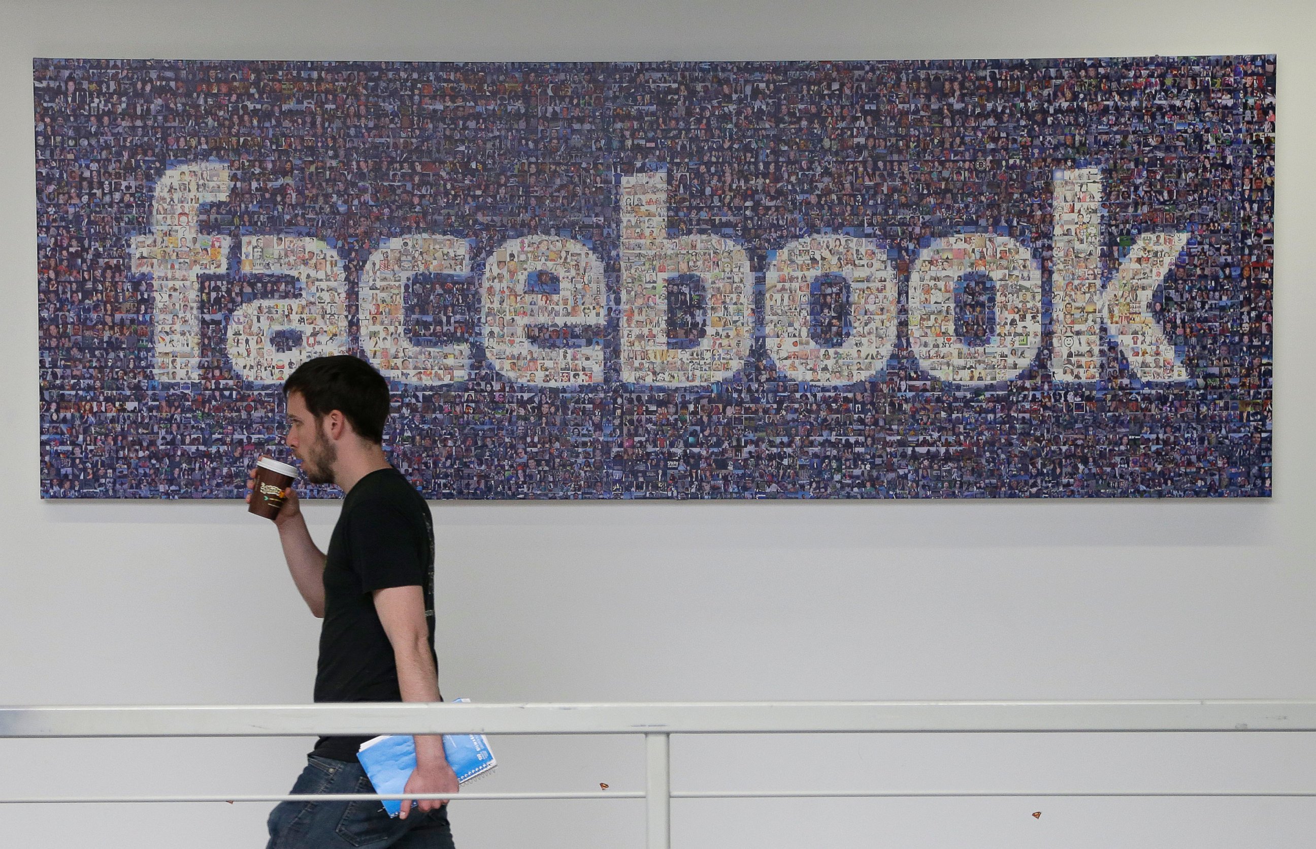 PHOTO: A Facebook employee walks past a sign at Facebook headquarters in Menlo Park, Calif., March 15, 2013.
