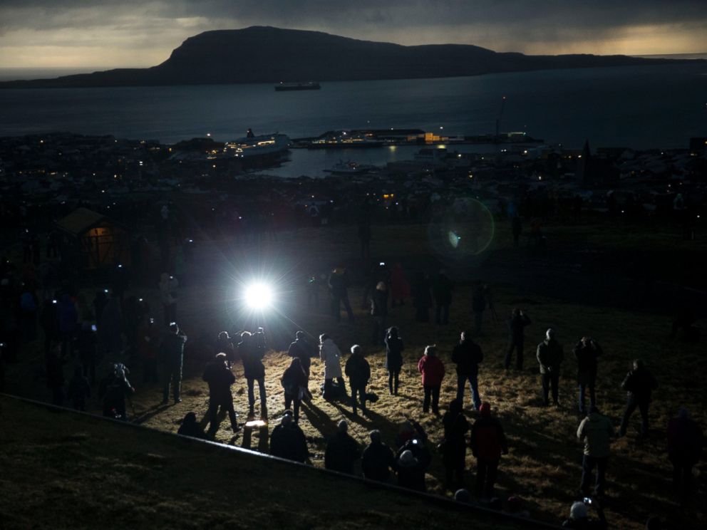 PHOTO: People watch in darkness during the totality of a solar eclipse on as seen from a hill beside a hotel on the edge of the city overlooking Torshavn, the capital city of the Faeroe Islands, March 20, 2015.