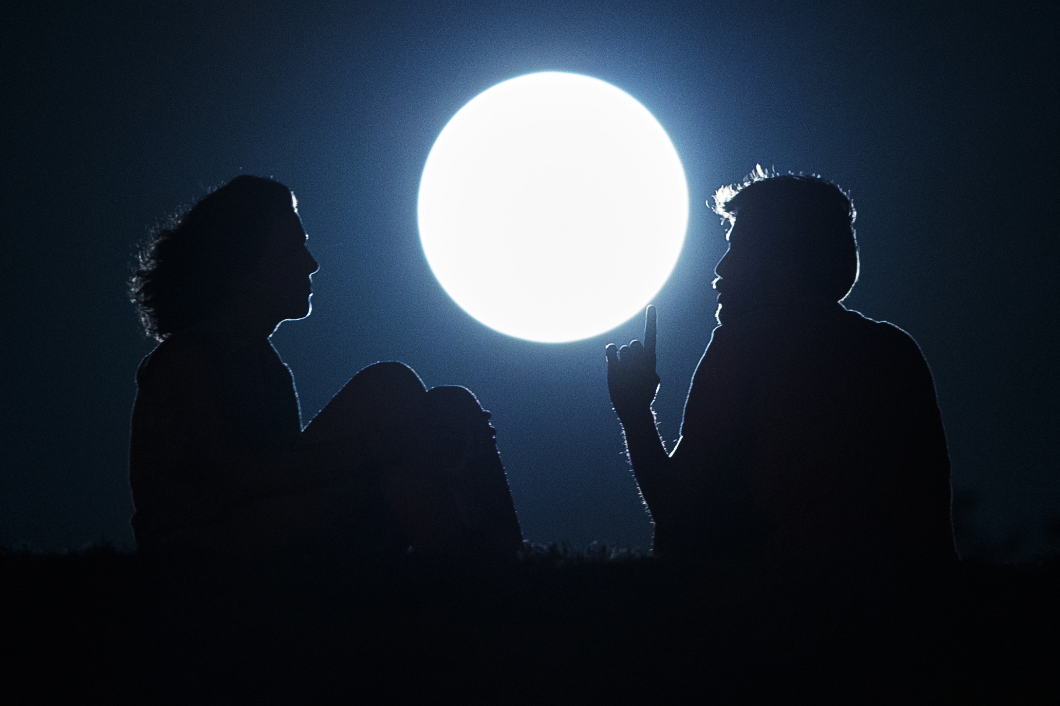 PHOTO: A couple talk as they sit against the perigee moon, also known as a supermoon, in Madrid, Aug. 10, 2014.