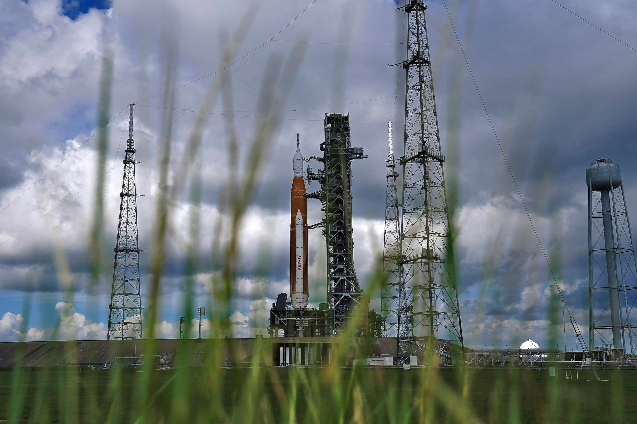 PHOTO: The Artemis 1 rocket is framed by tall grass as she stands ready on Launch Pad 39-B at the Kennedy Space Center, Aug. 26, 2022, in Cape Canaveral, Fla.
