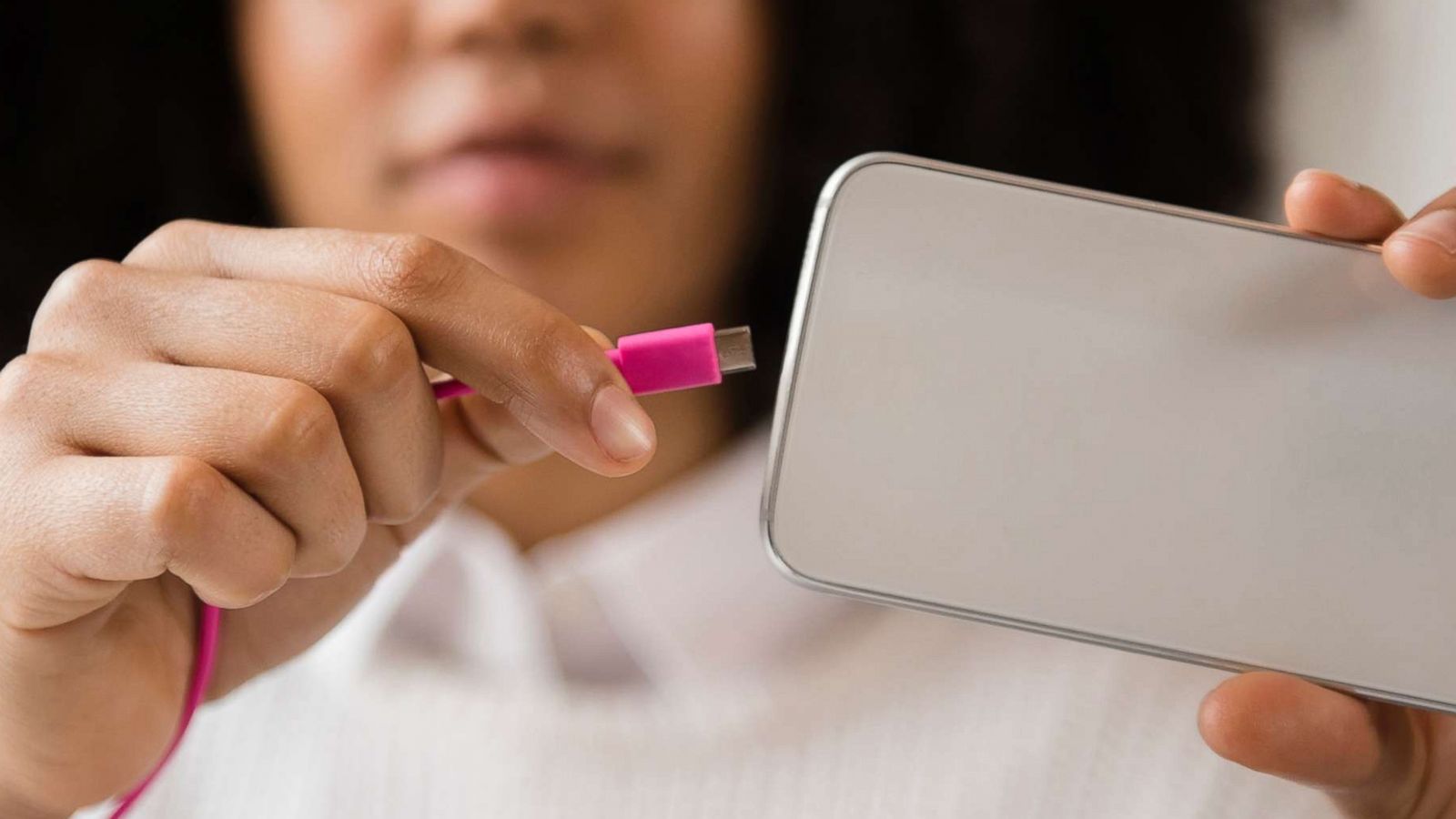 PHOTO: A woman connects a power cable to a mobile phone in an undated stock photo.