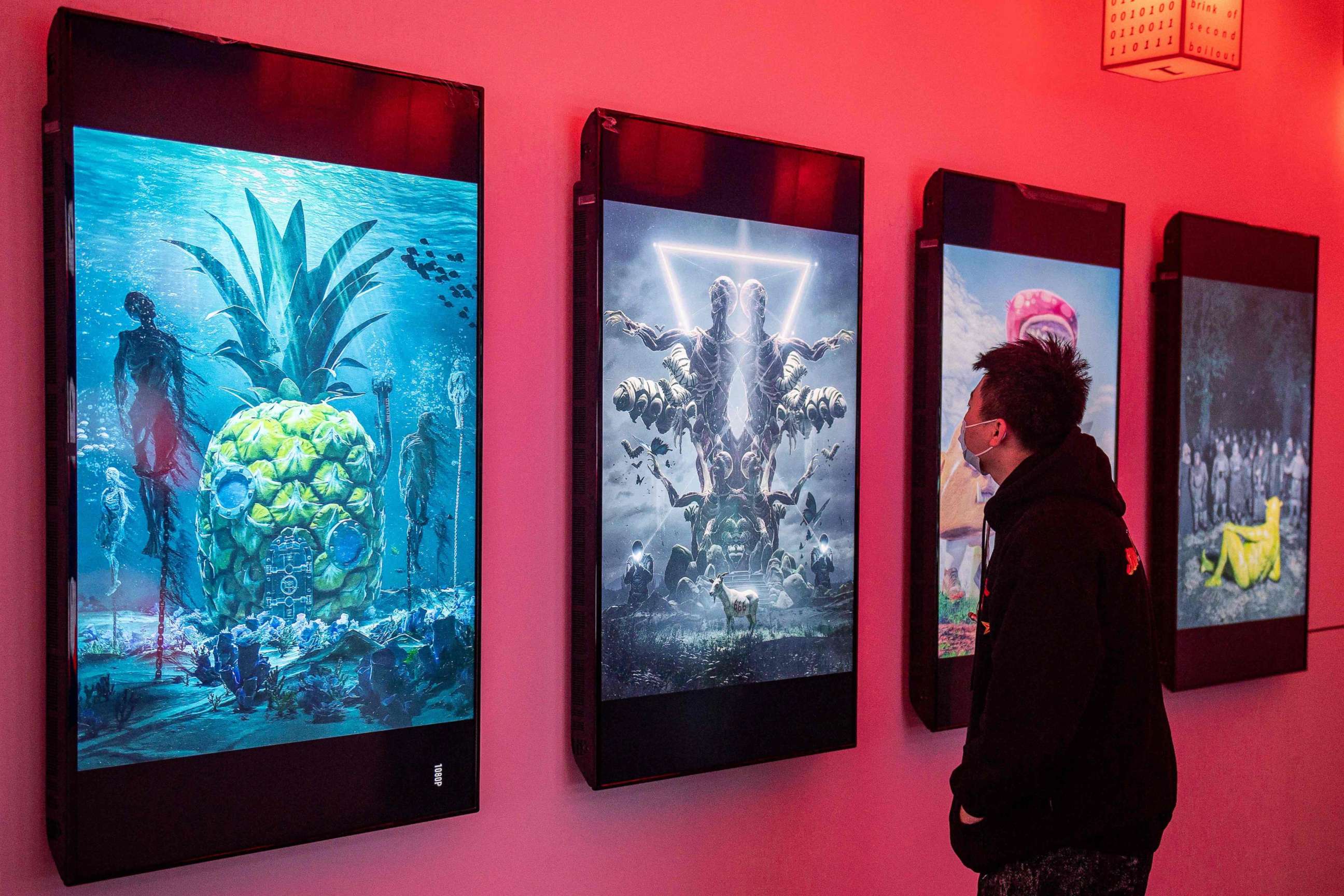 PHOTO: A man looks at digital paintings by U.S. artist Beeple at a crypto art exhibition entitled "Virtual Niche: Have You Ever Seen Memes in the Mirror?" ahead of its opening in Beijing on March 26, 2021.