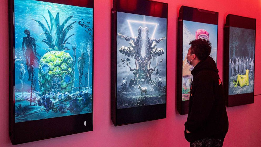 PHOTO: A man looks at digital paintings by U.S. artist Beeple at a crypto art exhibition entitled "Virtual Niche: Have You Ever Seen Memes in the Mirror?" ahead of its opening in Beijing on March 26, 2021.