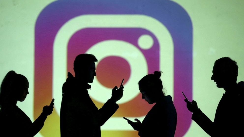 FILE PHOTO: Silhouettes of mobile users are seen next to a screen projection of Instagram logo in this picture illustration taken March 28, 2018. 