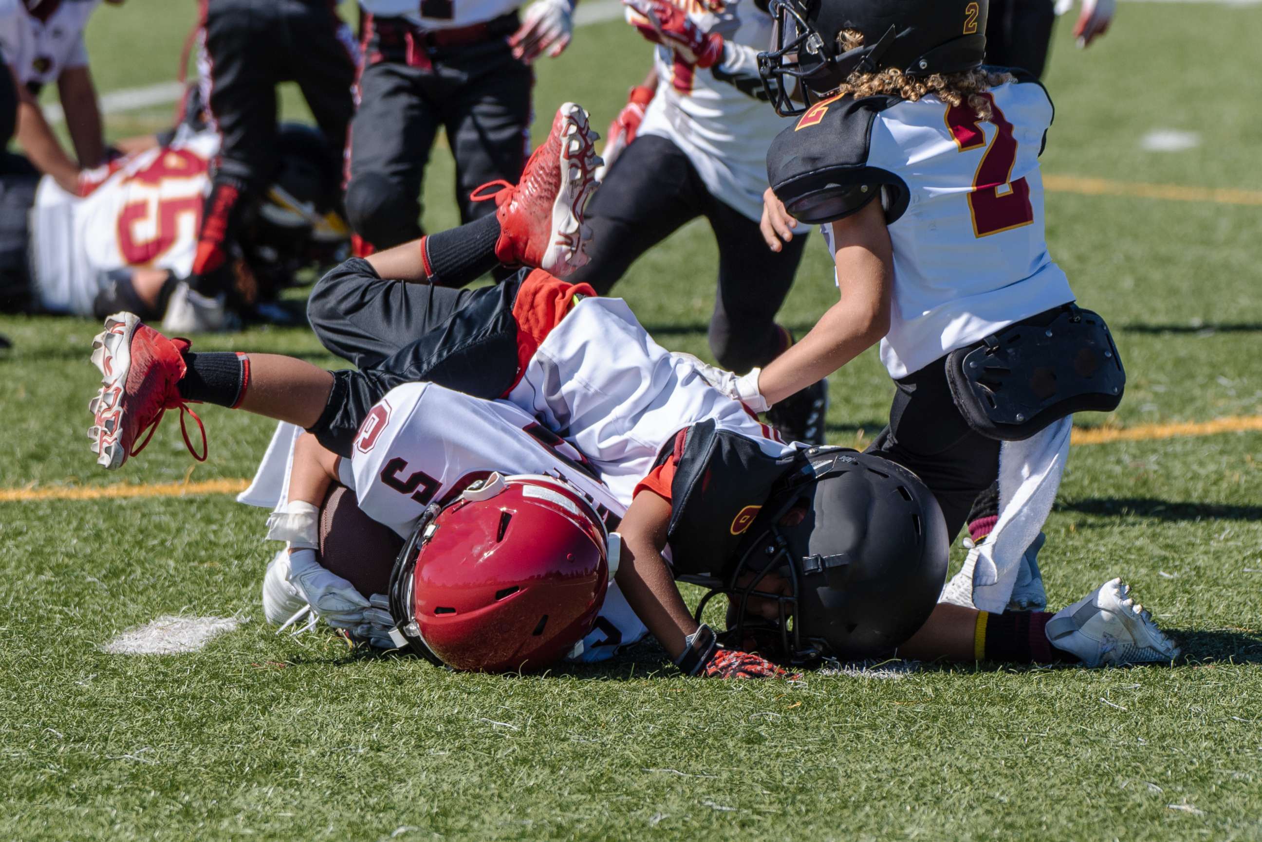 PHOTO: A youth football player is tackled and at bottom of a pile during a game.