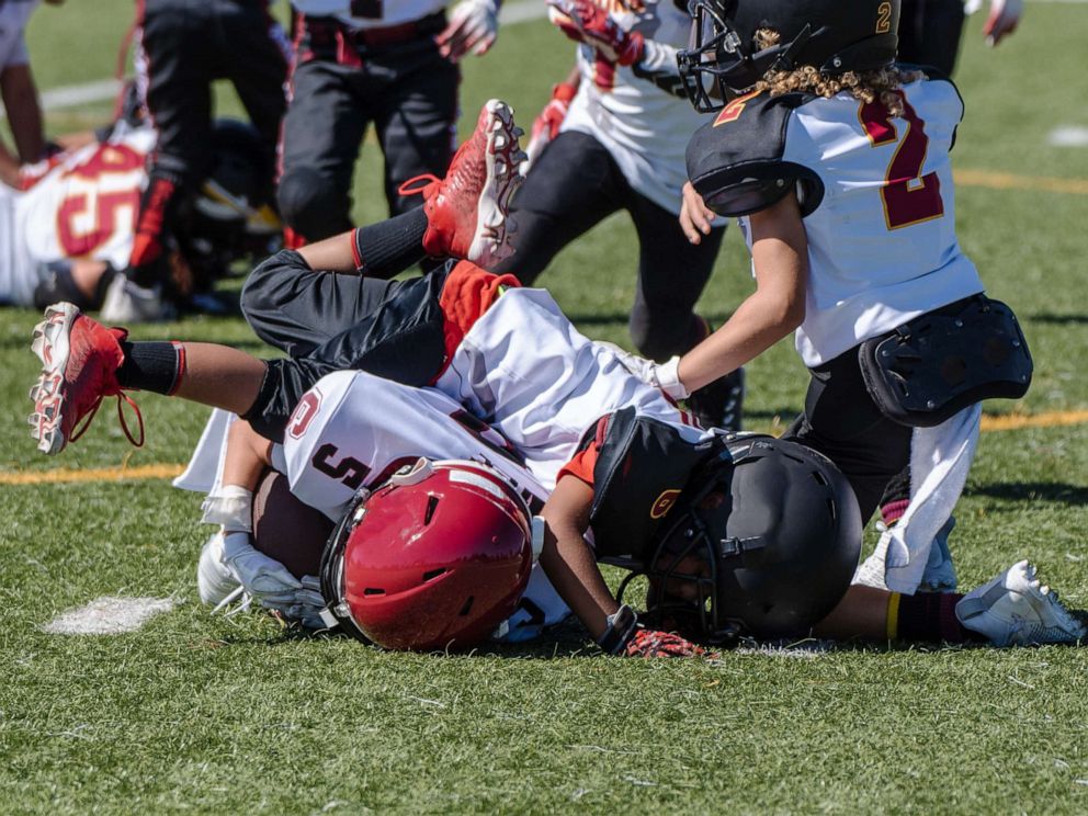 PHOTO: A youth football player is tackled and at bottom of a pile during a game.