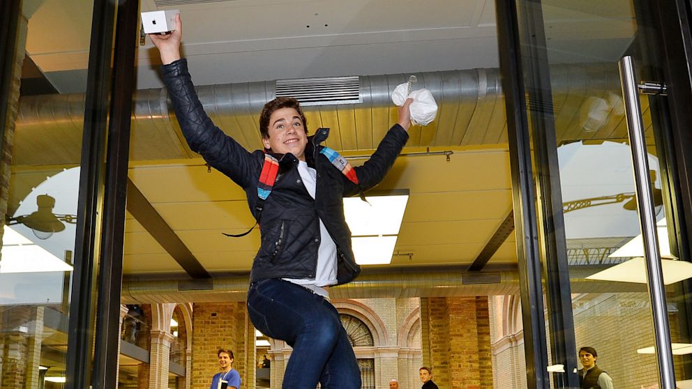 Jesse Green from London jumps as he leaves with his iPhone 5S after being the second person to enter the Apple store after they went on sale in central London, Sept. 20, 2013.  
