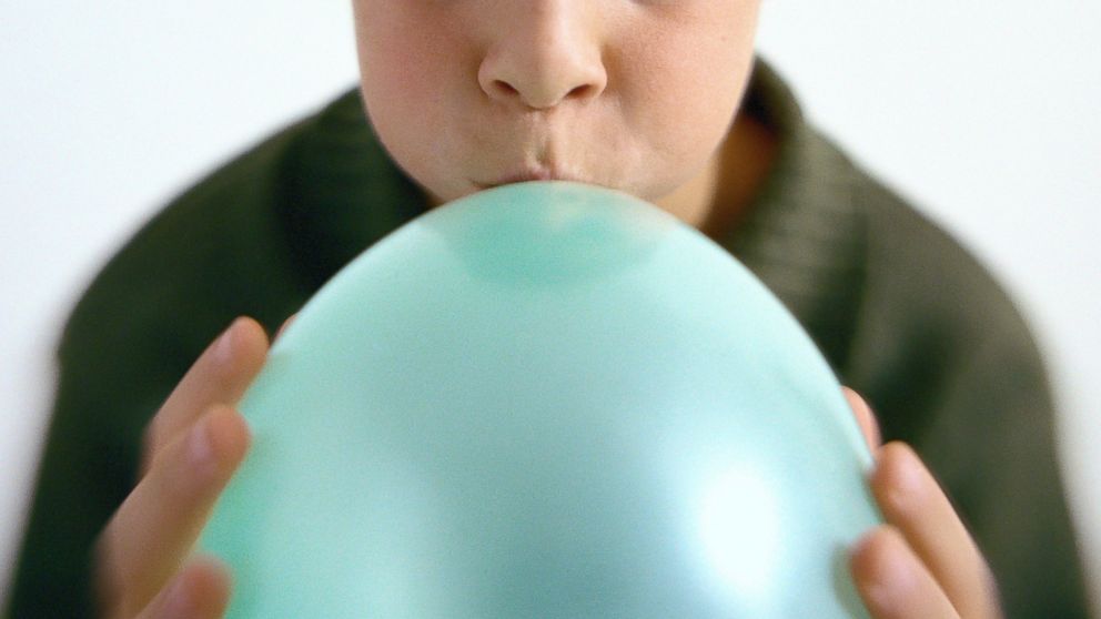 A boy blows up a balloon in an undated stock photo.