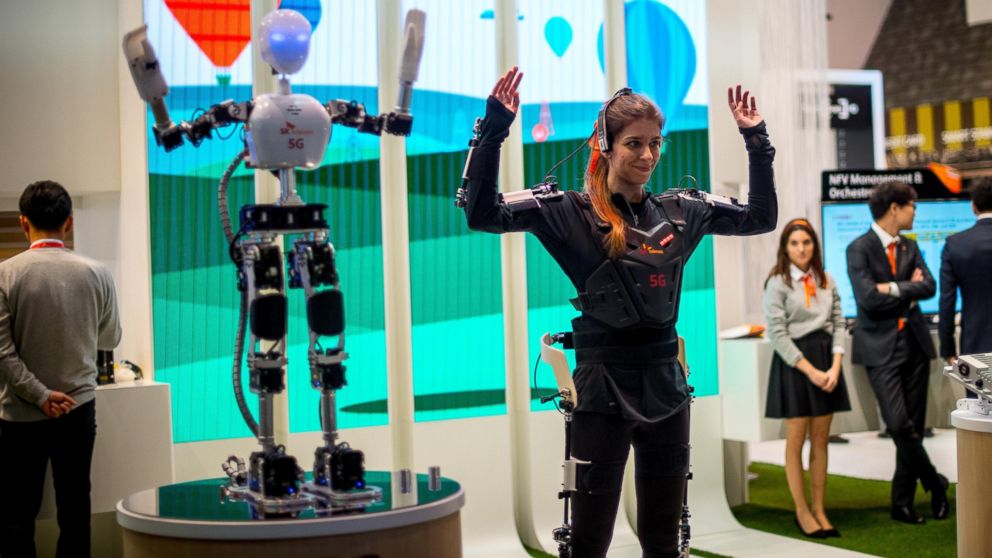 A hostess performs with robot under control by 5G Technology at the SK Telekom pavilion during the Mobile World Congress 2015, March 3, 2015 in Barcelona, Spain.
