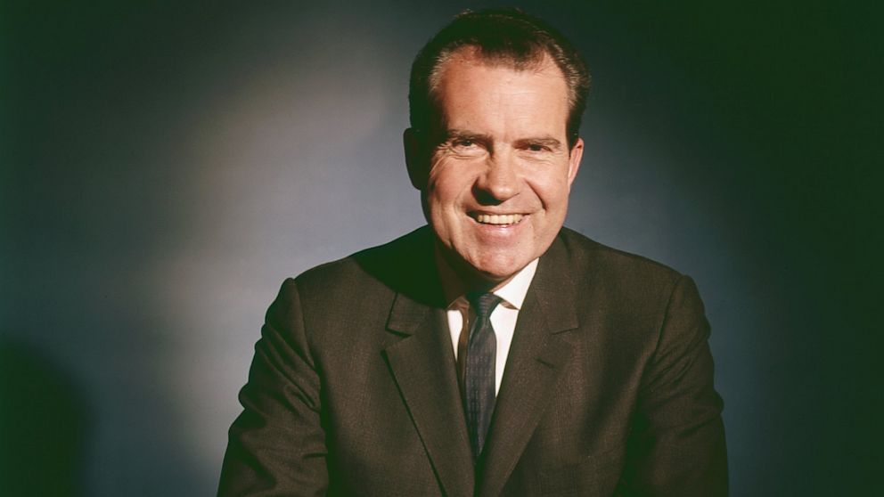PHOTO: Portrait of American politician and President Richard Nixon as he smiles and sits at a table, 1960s.