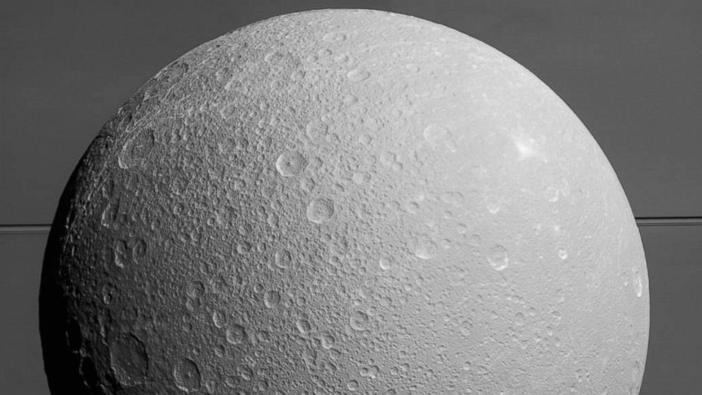 This view from NASA's Cassini spacecraft looks toward Saturn's icy moon Dione, with giant Saturn and its rings in the background, just prior to the mission's final close approach to the moon on August 17, 2015.